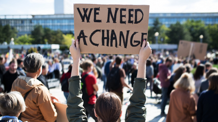 kartonnen bord met de tekst 'we need change'