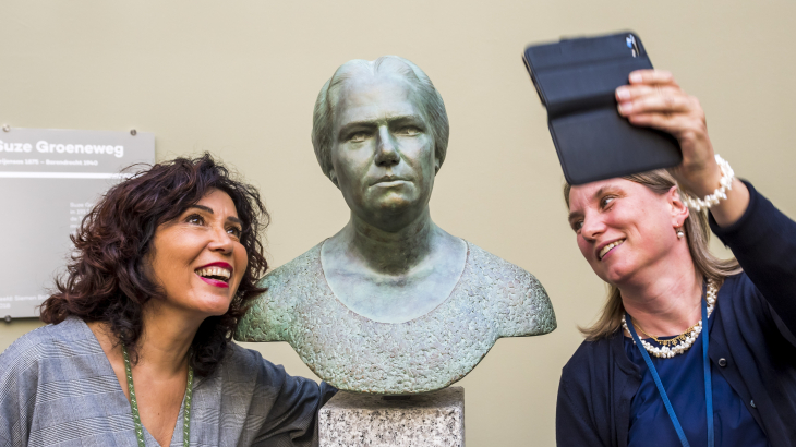 Twee vrouwen maken een foto tijdens de onthulling van het borstbeeld van Suze Groeneweg in de Tweede Kamer.