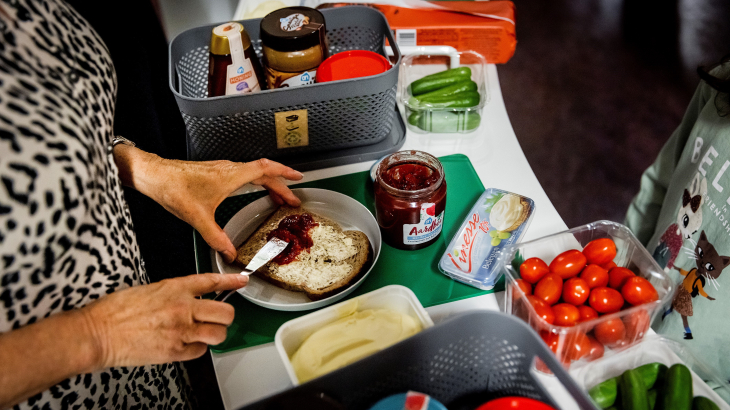 Een vrouw smeert brood. Je ziet haar gezicht niet.