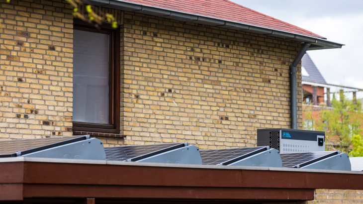 Een woning met zonnepanelen en een warmtepomp op het dak.