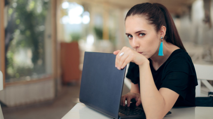 Vrouw achter laptop kijkt spiedend om zich heen