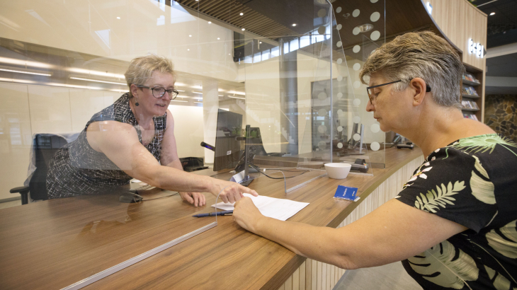 Een vrouw wordt geholpen bij een loket van het gemeentehuis. Foto: Joyce van Belkom (ANP)