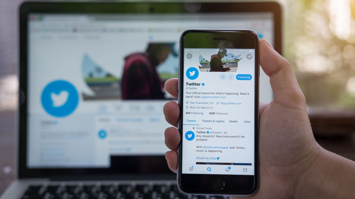 Laptop met Twitter en iphone in hand met Twitter op het scherm