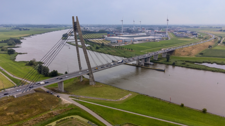 De Eilandbrug over de IJssel, met windturbines op de achtergrond.