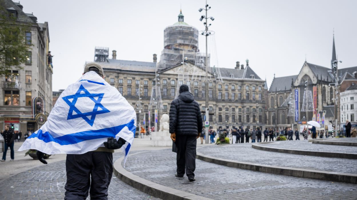 Man met Israëlische vlag over de schouders loopt over de Dam