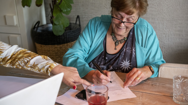 Een dame vult thuis aan de keukentafel formulieren in. Foto: Patricia Rehe/ANP