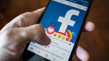 Hand houdt smartphone vast met Facebook erop