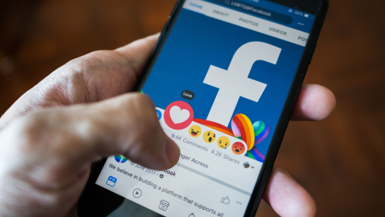 Hand houdt smartphone vast met Facebook erop