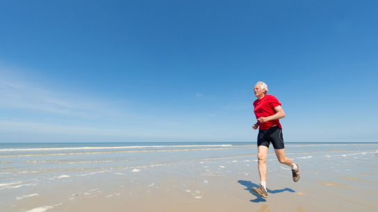 Oudere hardloper op het strand