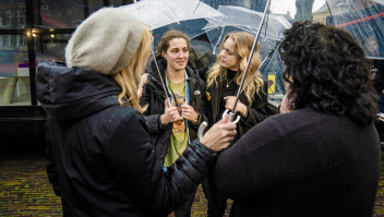 Twee jonge vrouwen onder een paraplu doen hun verhaal 