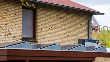 Een woning met zonnepanelen en een warmtepomp op het dak.