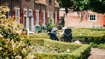Twee ouderen zitten op stoelen in een tuin. Foto: Joyce Huis
