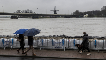 Mensen kijken naar het hoge water in de IJssel bij geplaatste zandzakken in Deventer. 