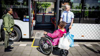 Een rolstoelgebruiker gaat met een speciale plank een bus in. Lang niet alle haltes zijn even toegankelijk. Foto: Robin Utrecht (ANP). 