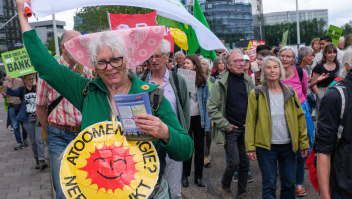 Tijdens een klimaatmars op de Zuidas in Amsterdam zwaait een vrouw met een klimaatvlag van de FNV, terwijl ze protesteert tegen kernenergie. Ook GroenLinks-PvdA liep mee.