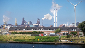 Een huizenrij op het Sluiseiland in het Noordzeekanaal, met op de achtergrond staalbedrijf Tata Steel.