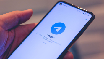 Hand met smartphone met logo Telegram op scherm