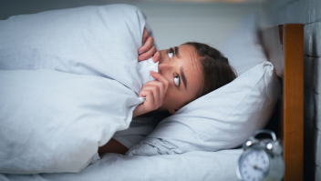 Vrouw ligt wakker met bang gezicht