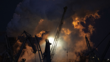 Een vlam van het affakkelen verlicht een uitgestoten stoomwolk op het Tata Steel terrein.