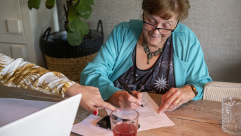 Een dame vult thuis aan de keukentafel formulieren in. Foto: Patricia Rehe/ANP