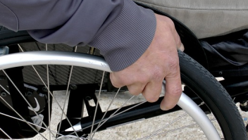 Een deel van een rolstoelwiel , de hand van de gebruiker houdt het wiel vast
